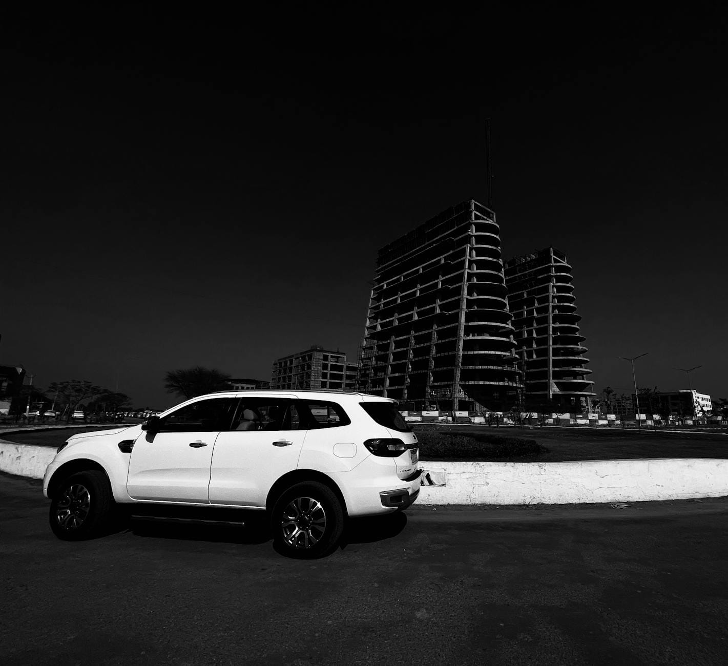 Białe SUV przy rondzie obok nowoczesnych budynków w budowie