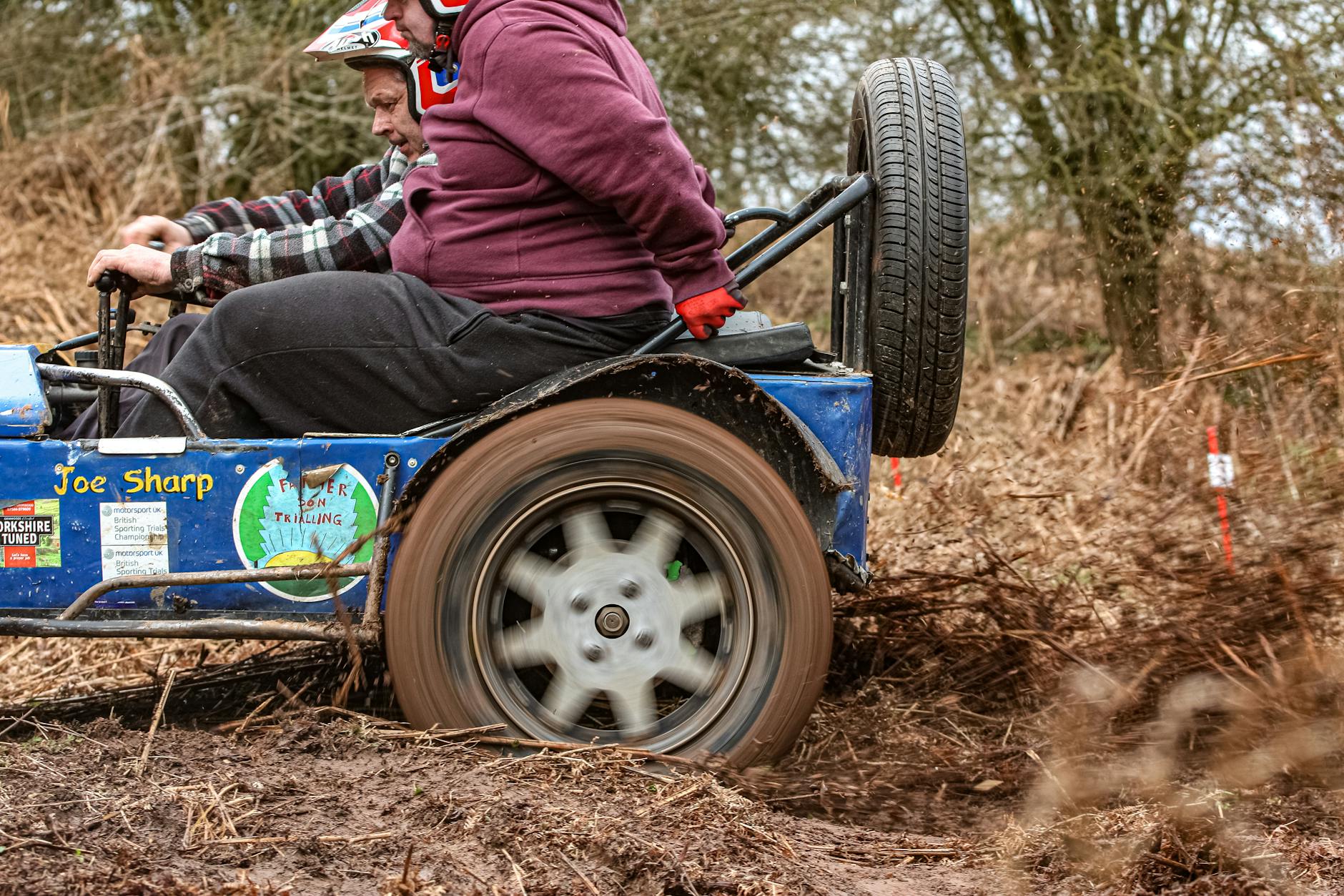 Dwóch mężczyzn w terenówce jadącej po błotnistym torze