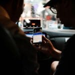 Kierowca i pasażer korzystają z nawigacji w smartfonie nocą w aucie