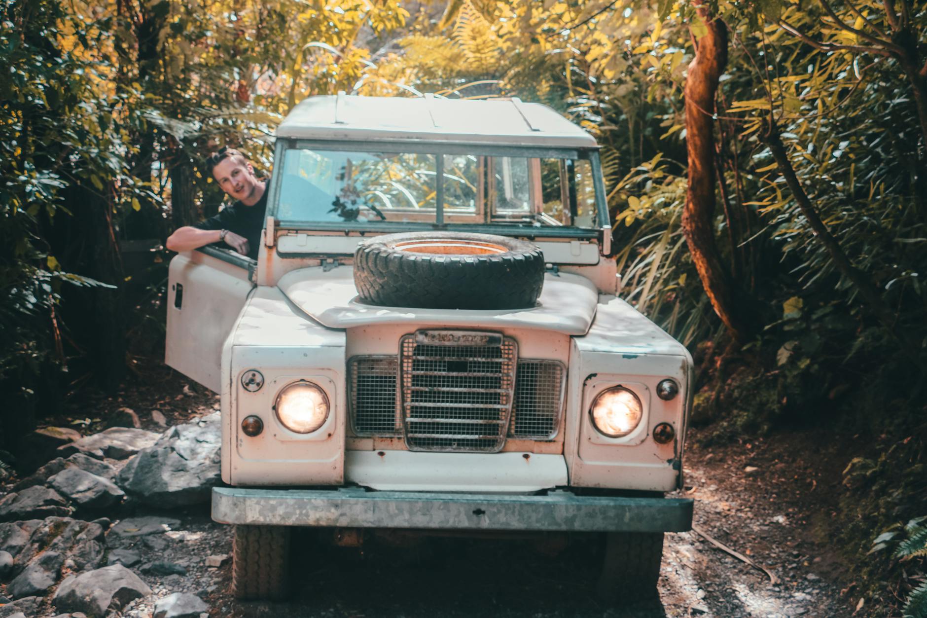 Klasyczny jeep 4x4 jedzie wąską drogą przez gęstą hawajską dżunglę