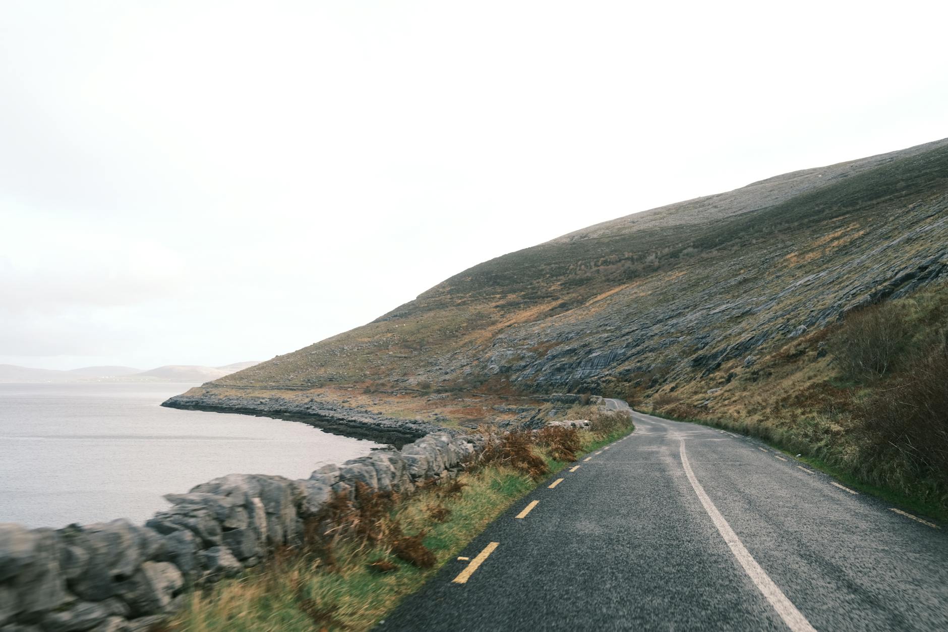 Mężczyzna z kacem pije piwo przy łóżku w zaciągniętym pokoju