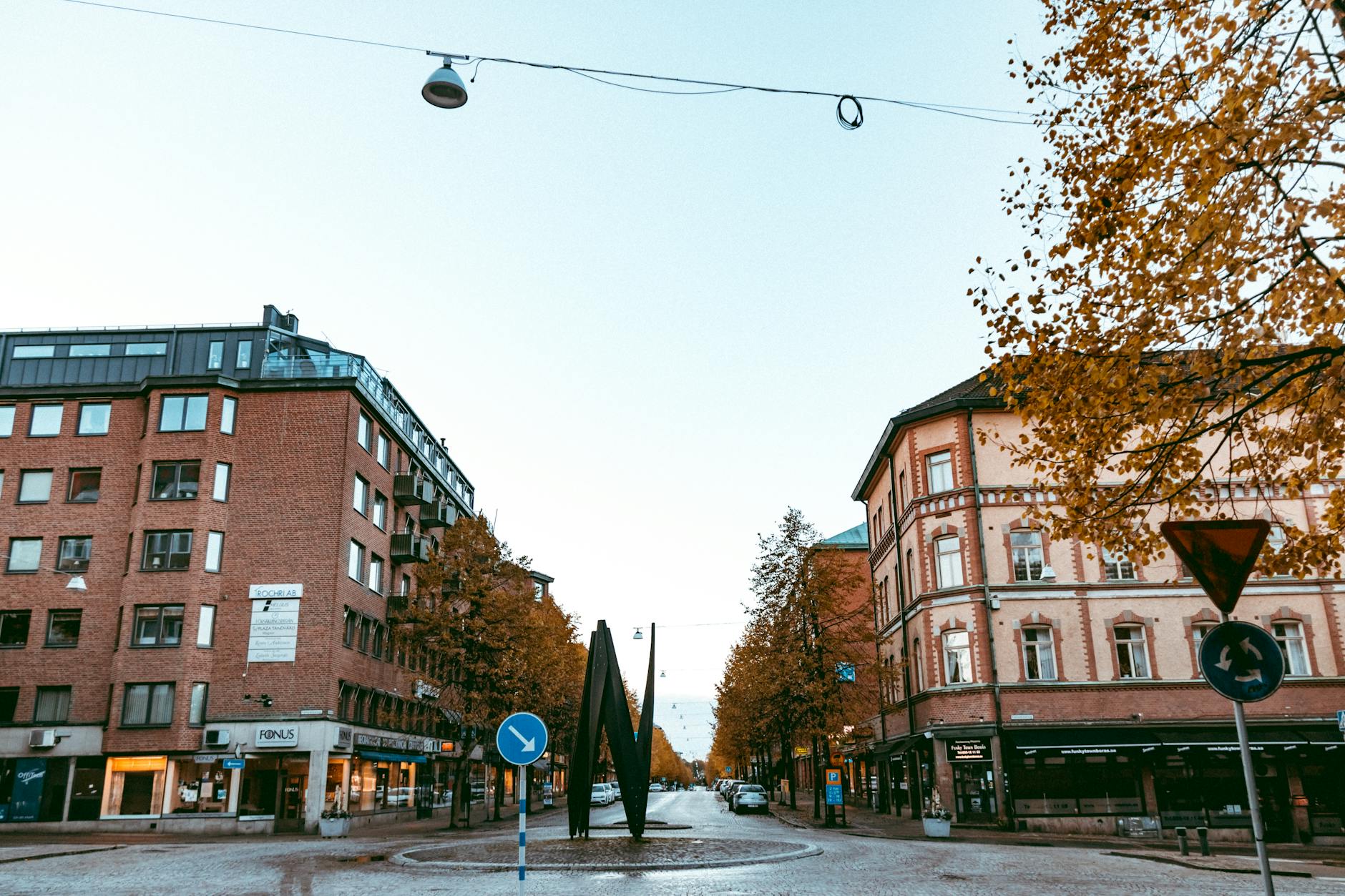 Rondo na miejskiej ulicy otoczone budynkami w słoneczny jesienny dzień