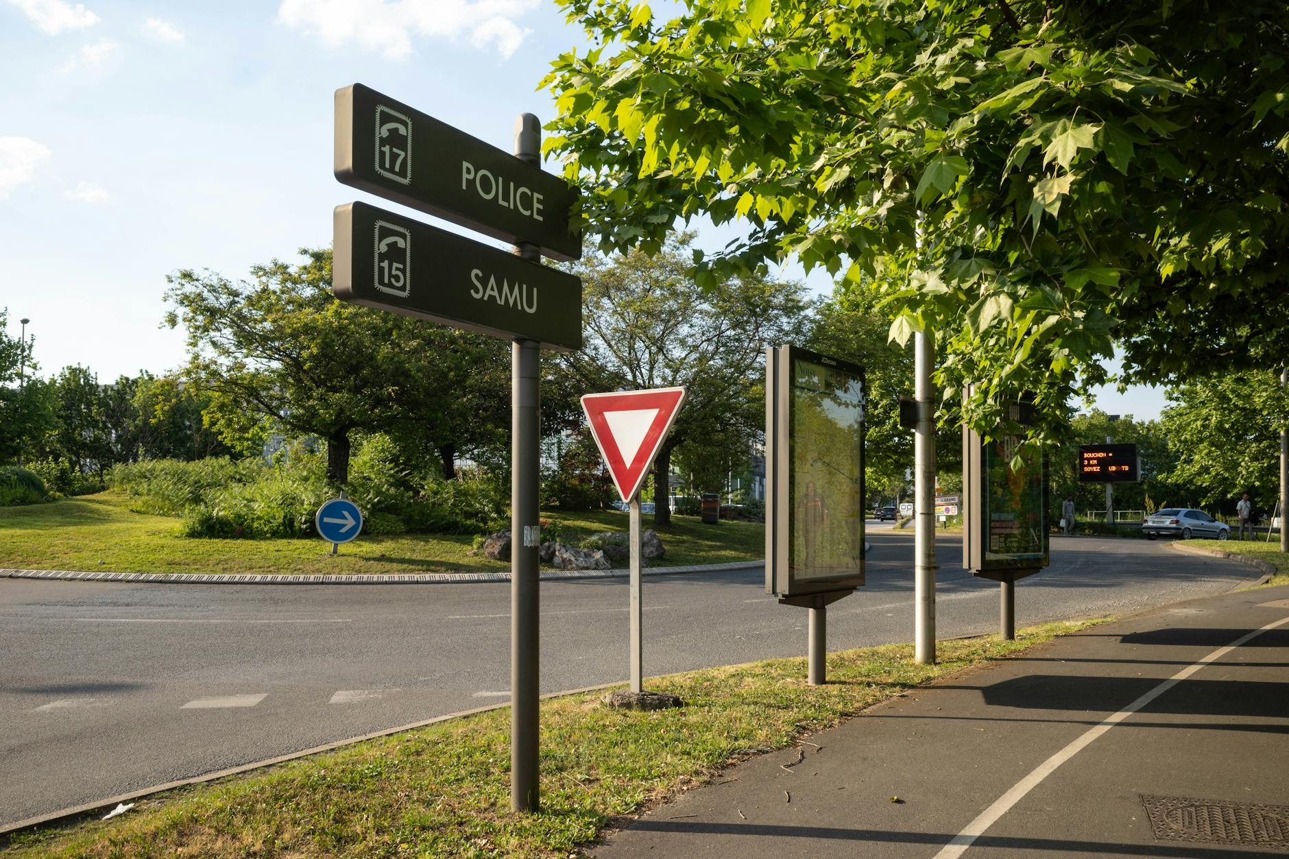 Rondo we Francji z znakami drogowymi otoczone bujną zielenią