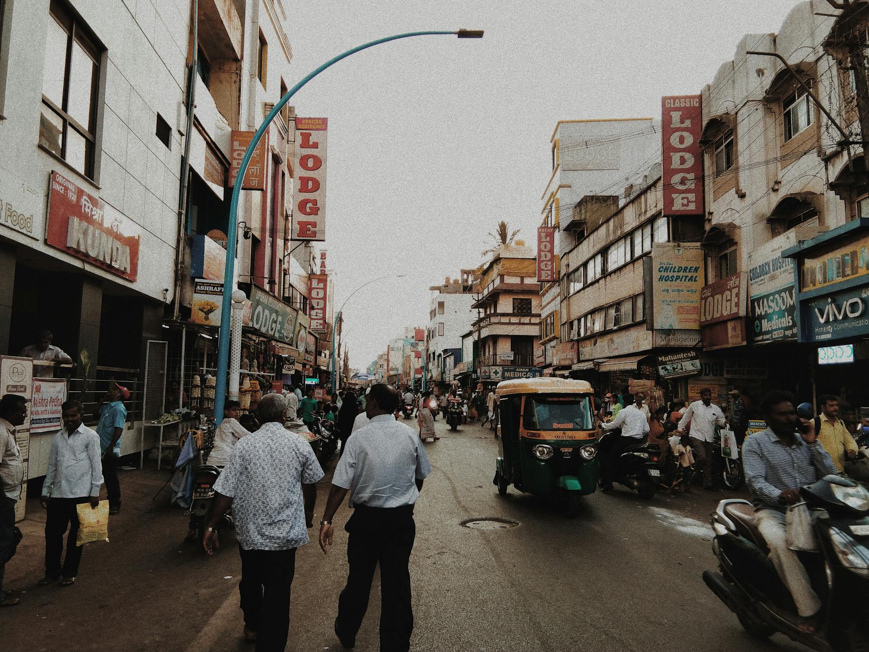 Ruchliwa ulica w Indiach z pieszymi, sklepami i motocyklami