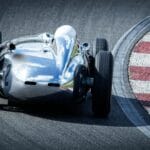 Srebrny samochód wyścigowy pokonuje zakręt toru