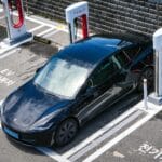 Czarny samochód elektryczny przy ładowarce w mieście