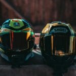 Dwa kolorowe kaski motocyklowe z lustrzanymi szybami na stole na zewnątrz