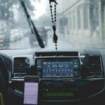 Kierowca w deszczu jedzie przez miasto, korzystając z telefonu na desce