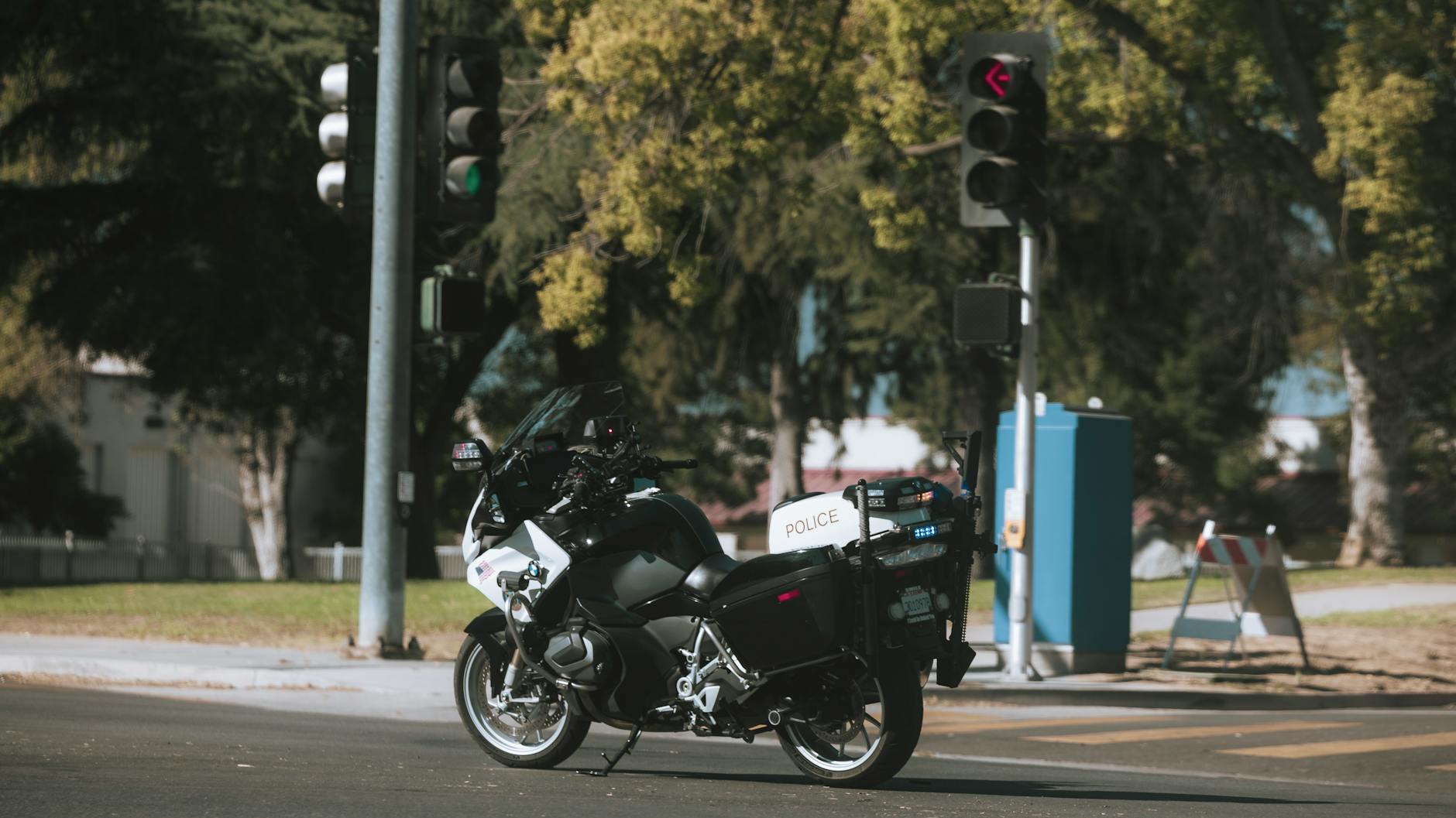 Policyjny motocykl zatrzymany na skrzyżowaniu z sygnalizacją w mieście