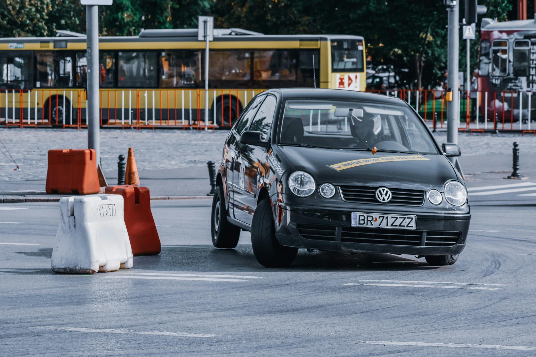 Czarny samochód jedzie szybko po drodze z pachołkami w mieście