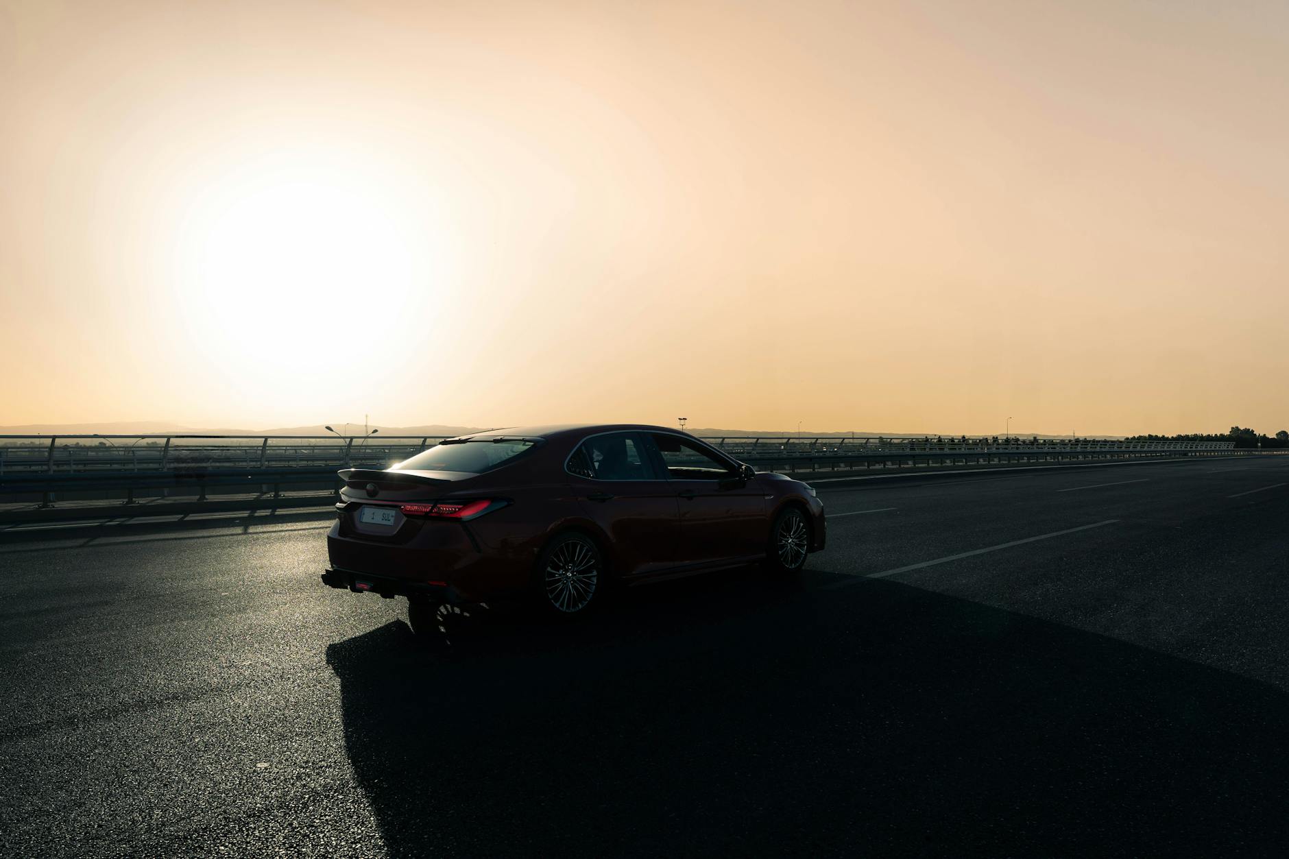 Czerwony samochód jedzie pustą autostradą o zachodzie słońca