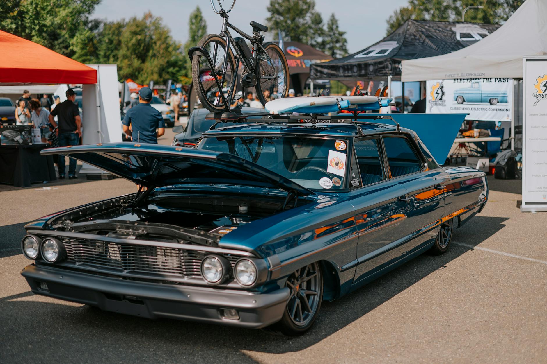 Zabytkowy samochód z rowerem na dachu podczas plenerowego zlotu