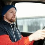 Czy naprawdę jeździsz dobrze? Brodaty mężczyzna w kapturze prowadzi auto z dużą koncentracją