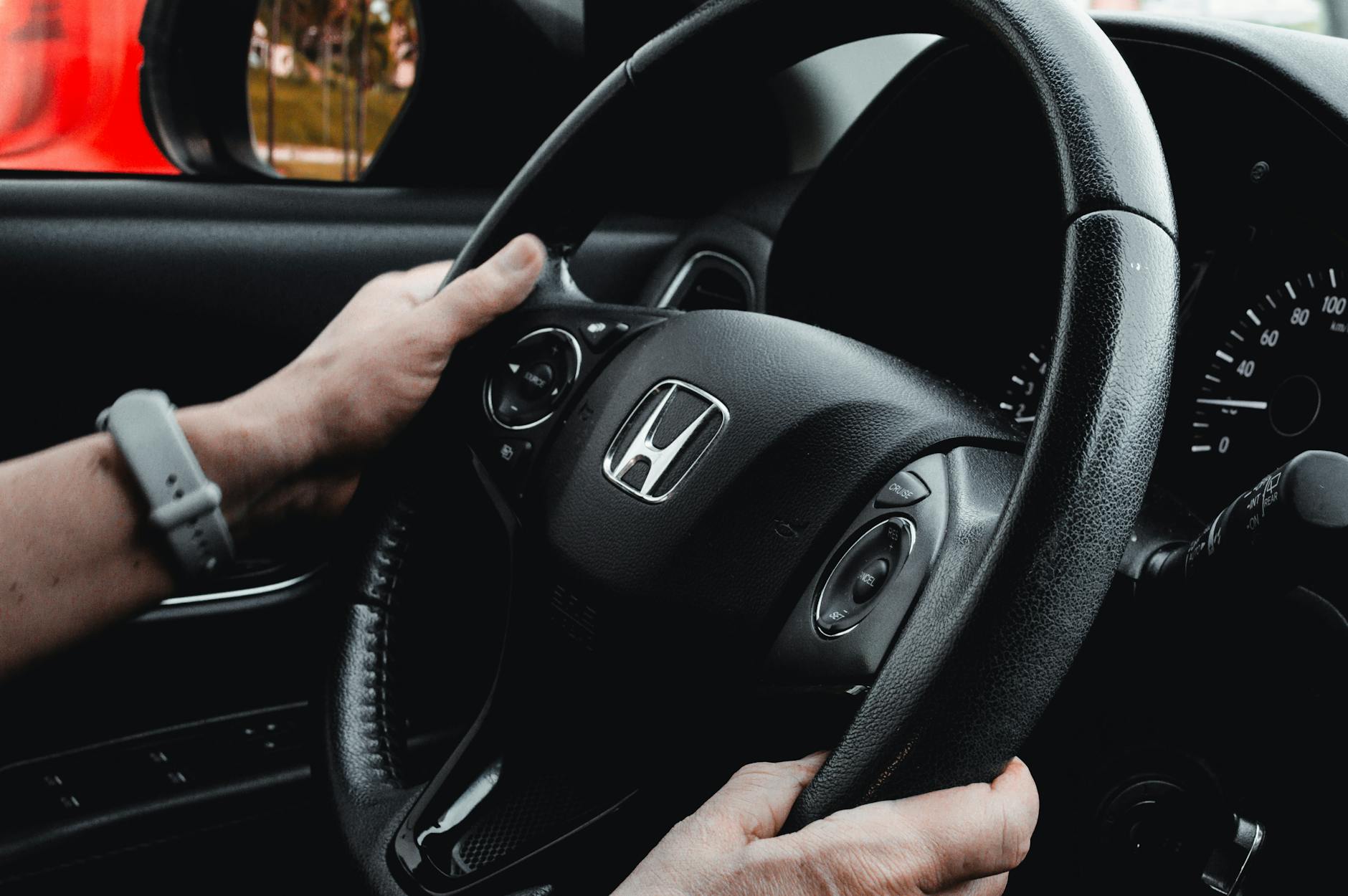 Kierowca trzyma kierownicę, widoczna deska rozdzielcza auta