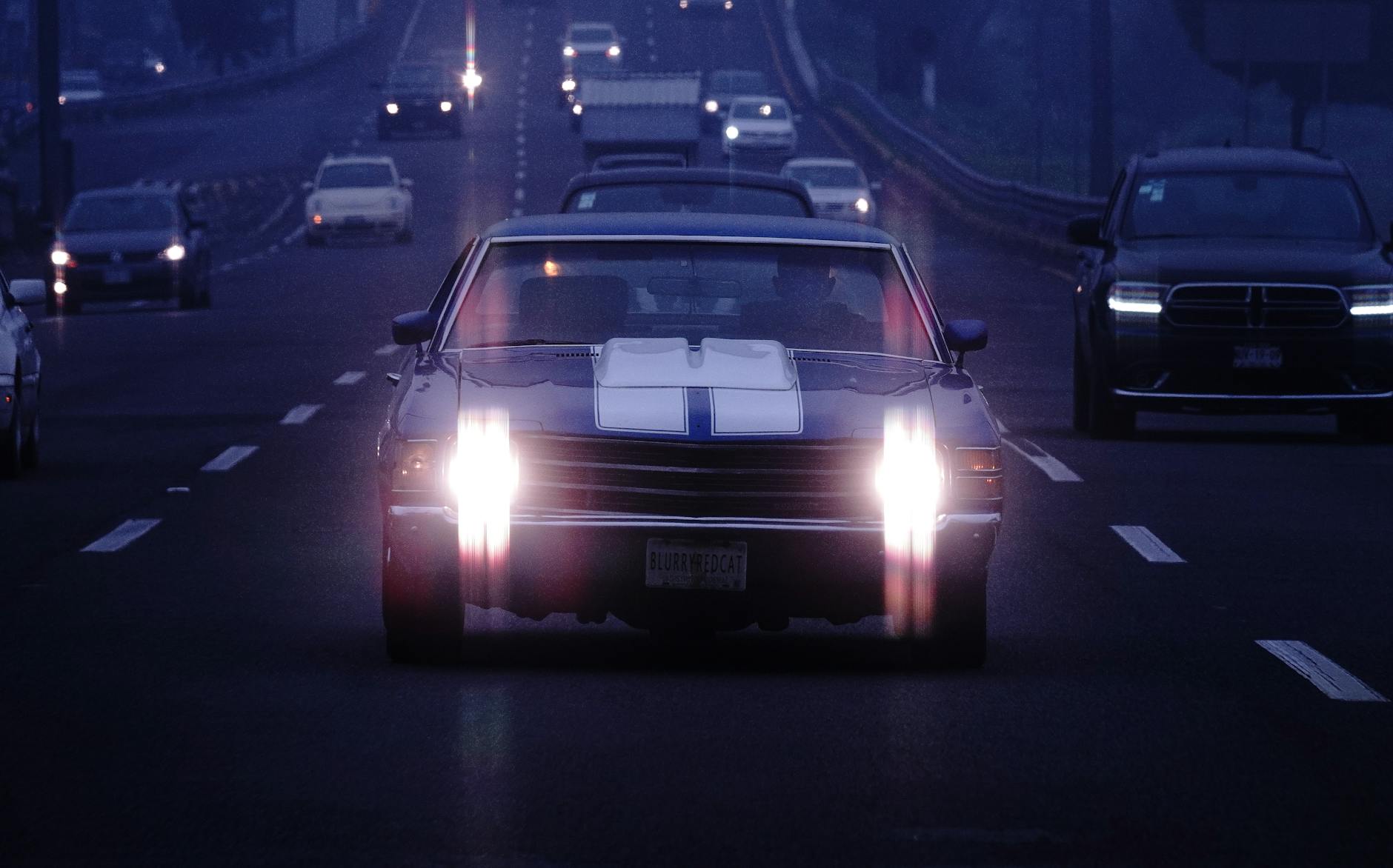 Klasyczny samochód na nocnej autostradzie z włączonymi światłami