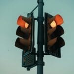 Żółte światło na sygnalizatorze: czy zawsze trzeba hamować? Co mówią przepisy Sygnalizator świetlny z żółtym światłem na tle wieczornego miasta