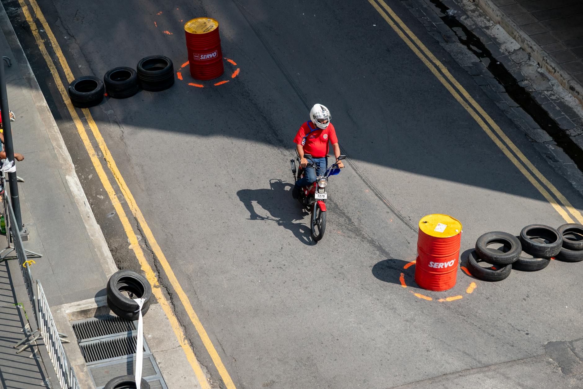 Motocyklista na placu manewrowym między pachołkami i barierami