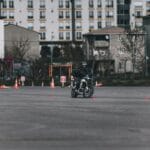 Motocyklista na placu manewrowym omija pachołki w mieście