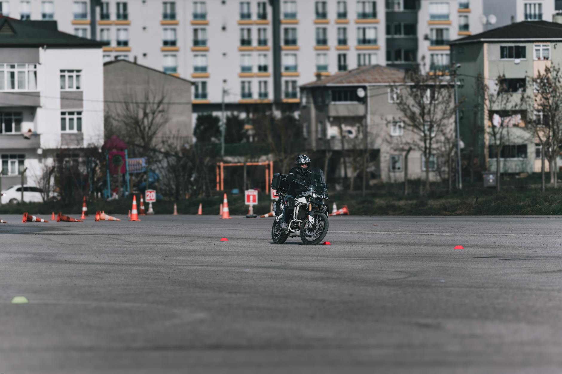 Motocyklista na placu manewrowym omija pachołki w mieście