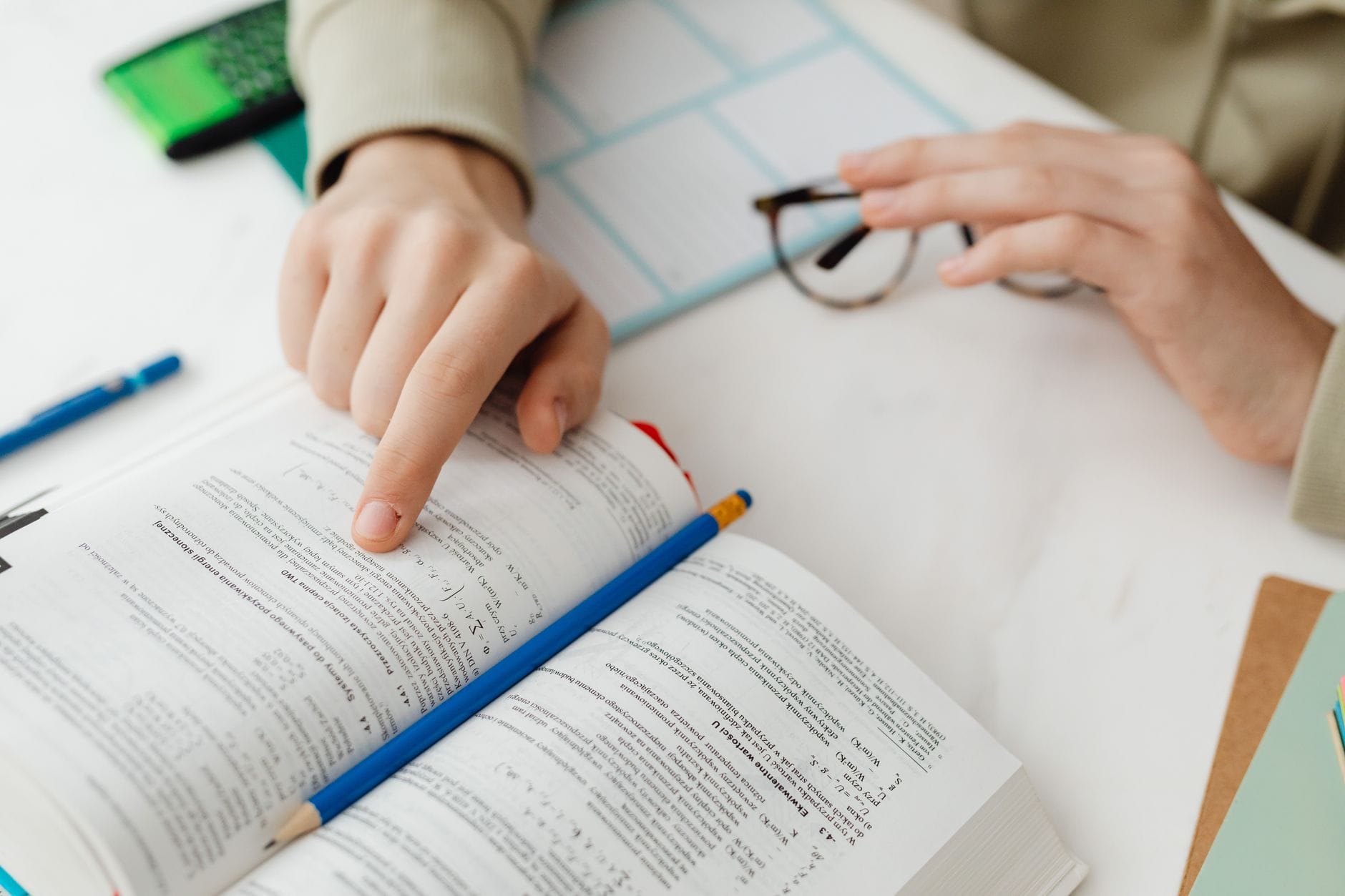 Uczeń przy biurku uczy się z podręcznika, robi notatki ołówkiem